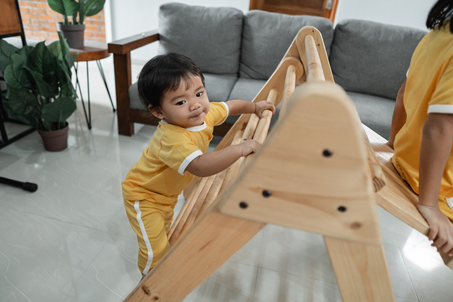 Little Kids Climb on the Pikler Triangle Toy While Playing Together